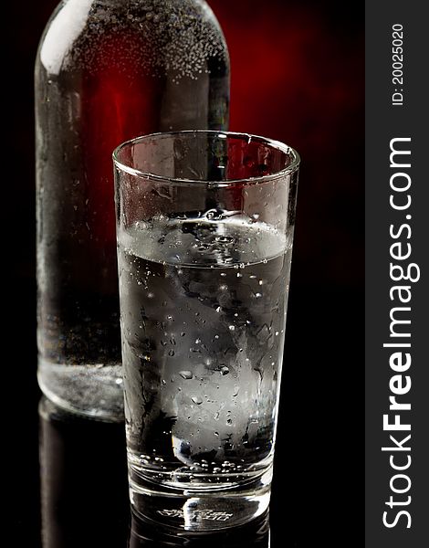 Photo of water glass and bottle standing on black glass table