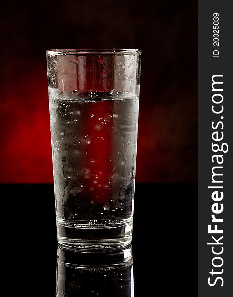 Photo of a water glass with sparkling cold water inside on black glass table