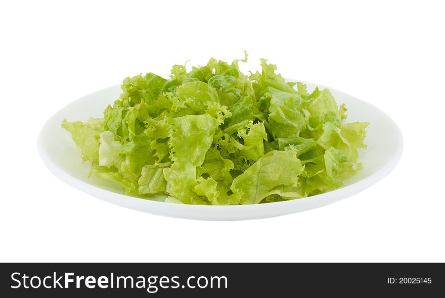 The cut green salad in a plate on a white background. The cut green salad in a plate on a white background.