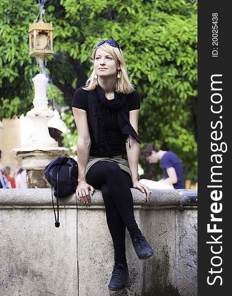 Beautiful young lady sitting at the edge of the fountain at the main square in Cordoba, Spain. Beautiful young lady sitting at the edge of the fountain at the main square in Cordoba, Spain.