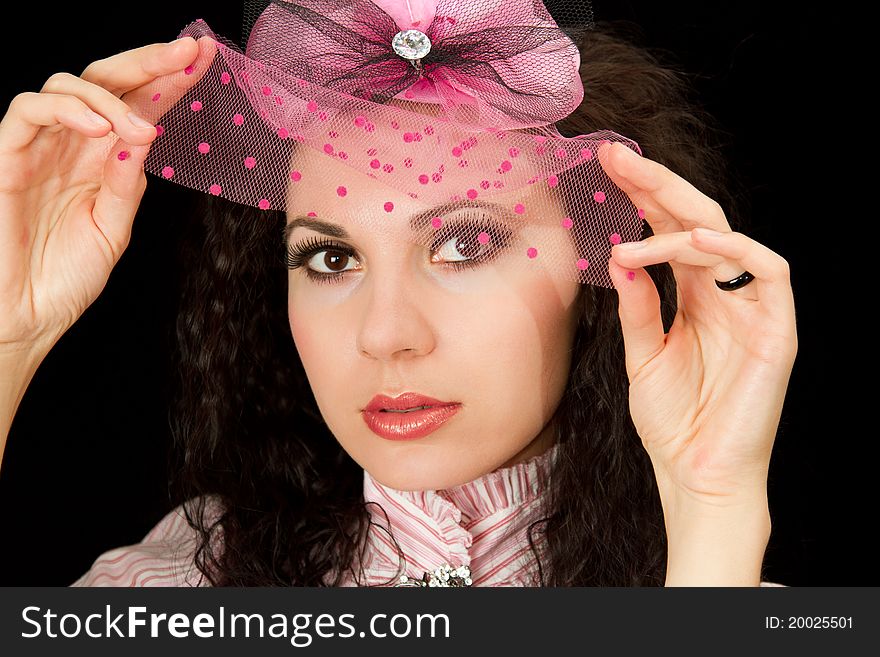 beautiful woman in a pink hat with a veil on an isolated black background. beautiful woman in a pink hat with a veil on an isolated black background