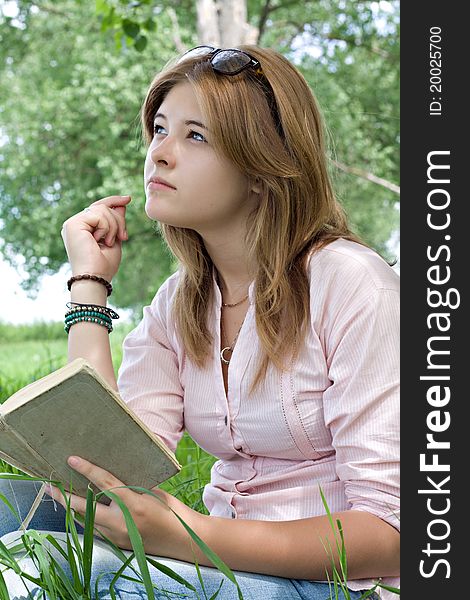 Teenager girl reading book in park