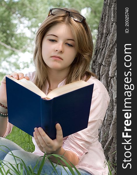 Teenager girl reading book in park