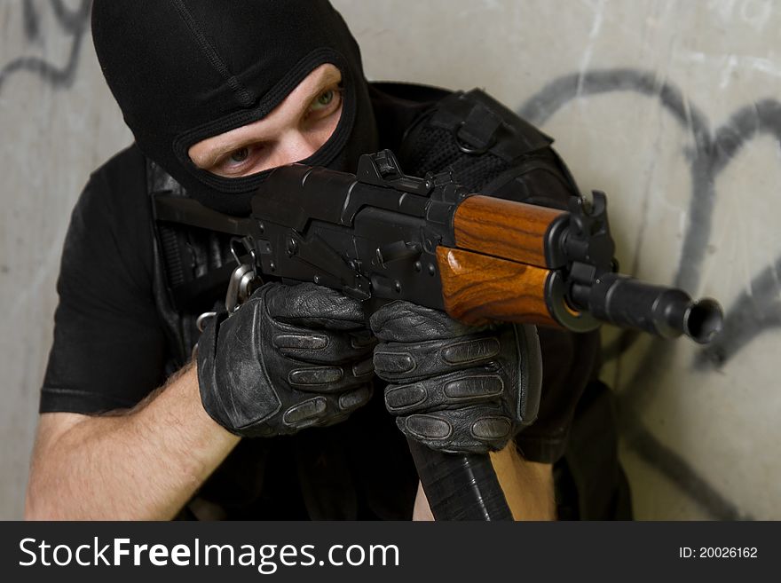 Soldier in black mask targeting with AK-47 rifle