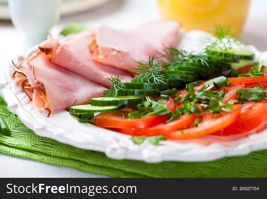 Ham,tomatoes and cucumber with fresh herbs on a plate. Ham,tomatoes and cucumber with fresh herbs on a plate