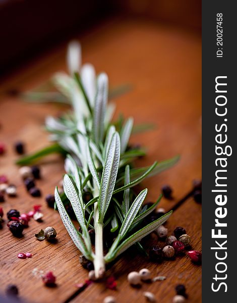 Fresh rosemary sprigs and peppercorns on wooden background. Fresh rosemary sprigs and peppercorns on wooden background