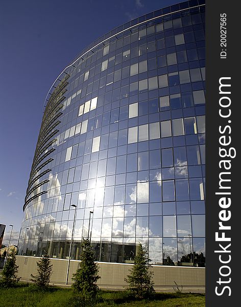 Modern oval office building made of glass with clouds reflection on the surface. Modern oval office building made of glass with clouds reflection on the surface