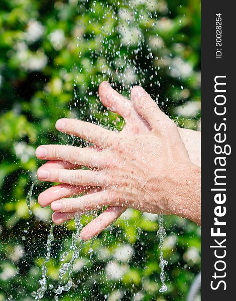 Washing hands under falling water on a green background. Washing hands under falling water on a green background