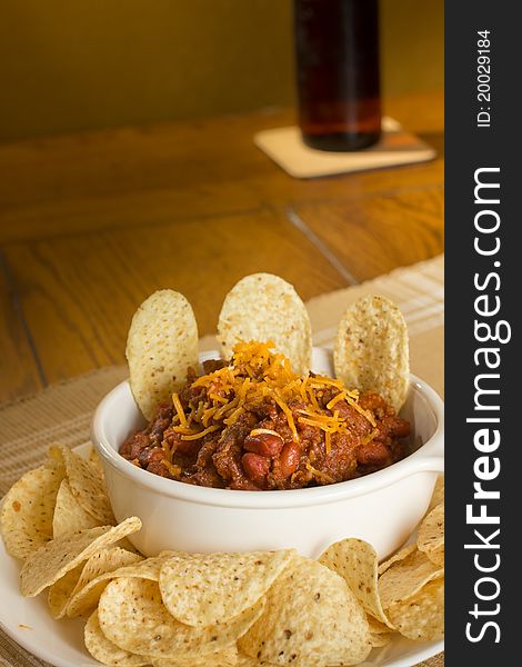 A bowl of chili con carne served with tortilla chips and a bottle of beer. A bowl of chili con carne served with tortilla chips and a bottle of beer