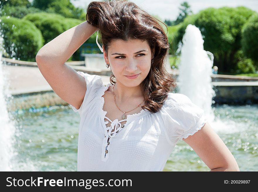 Beautiful girl at the fountain in summer