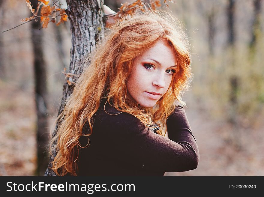 The red-haired girl in autumn leaves outdoor shot
