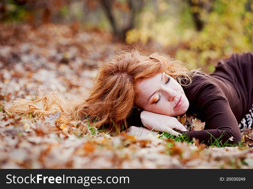 The red-haired girl in autumn leaves outdoor shot