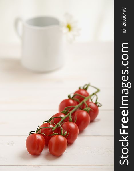 Cherry tomatoes on a white table, white flower in background