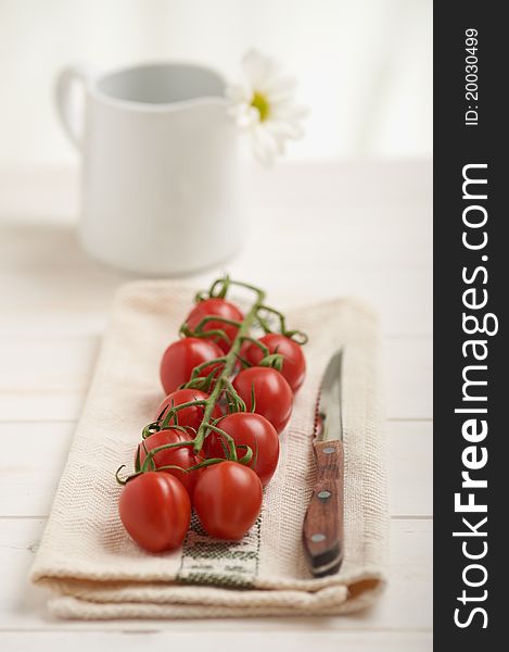 Cherry tomatoes on a white table, white flower in background