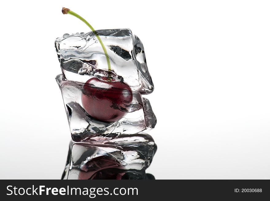 Cherry on ice cube, white background with reflection