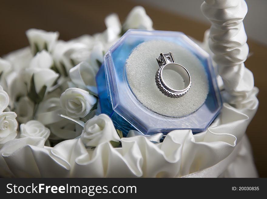 A wedding ring in a basket full of roses.