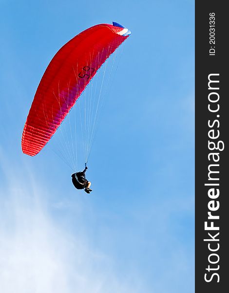 Red Paraglider Flying In Blue Sky