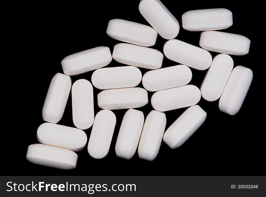 A pile of similar pills on a black background. A pile of similar pills on a black background.