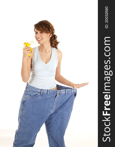 A woman holding out her big pants happy with how she lost weight, as she is holding a banana. A woman holding out her big pants happy with how she lost weight, as she is holding a banana.