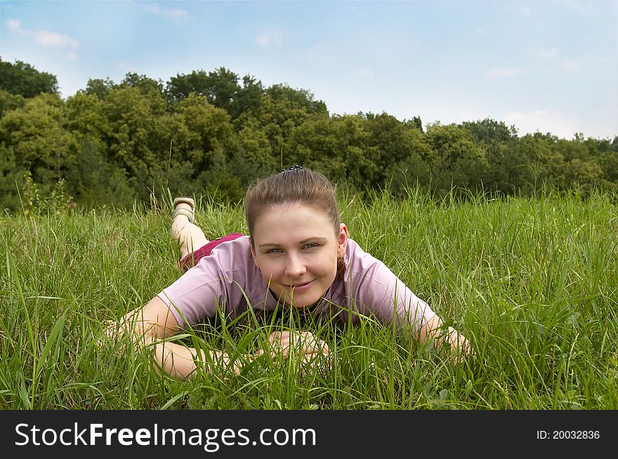 Young smiling woman lying on the grass in the park. Young smiling woman lying on the grass in the park