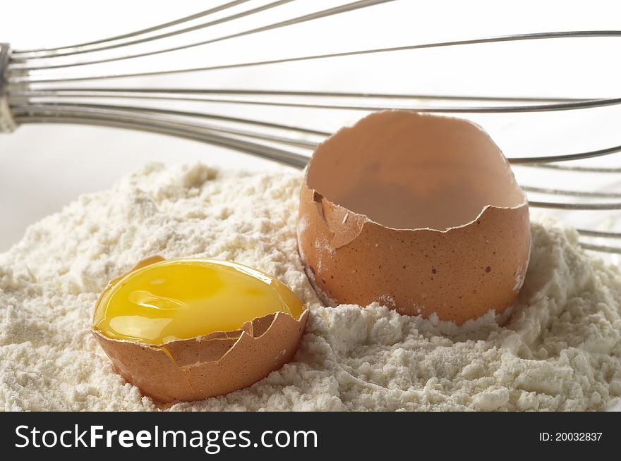 Flour pile, egg and metal whisker fragment over gray gradient background. Flour pile, egg and metal whisker fragment over gray gradient background