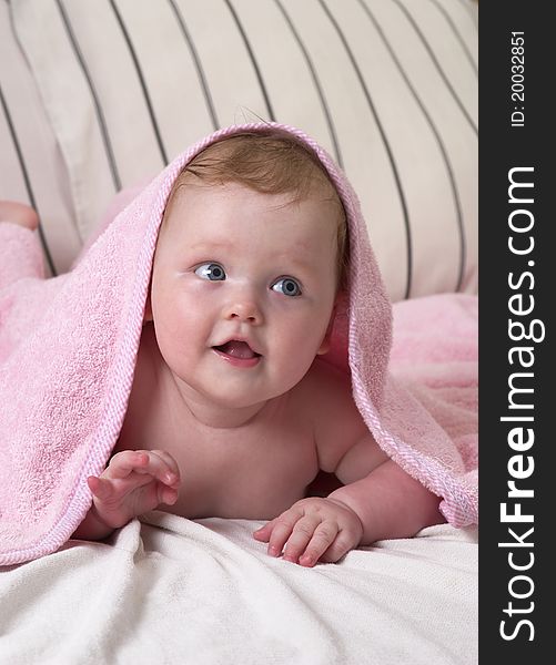 Little baby girl under soft pink towel