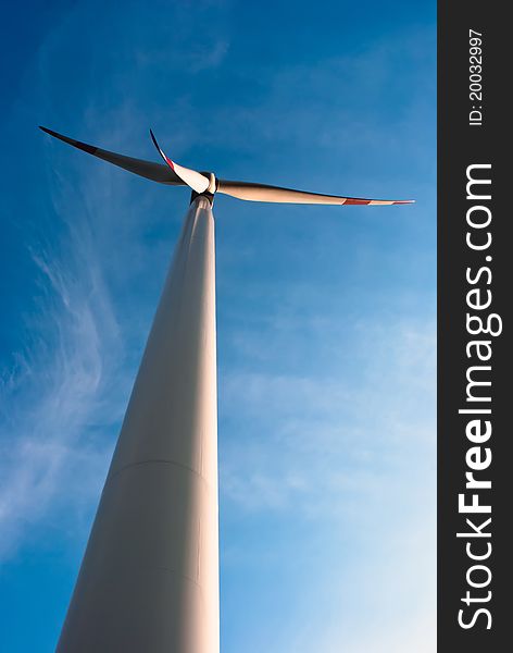 A big wind turbine stands in front of blue sky with clouds. A big wind turbine stands in front of blue sky with clouds