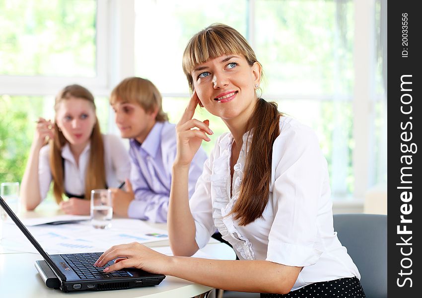 Young business woman working in office with collegues on background. Young business woman working in office with collegues on background