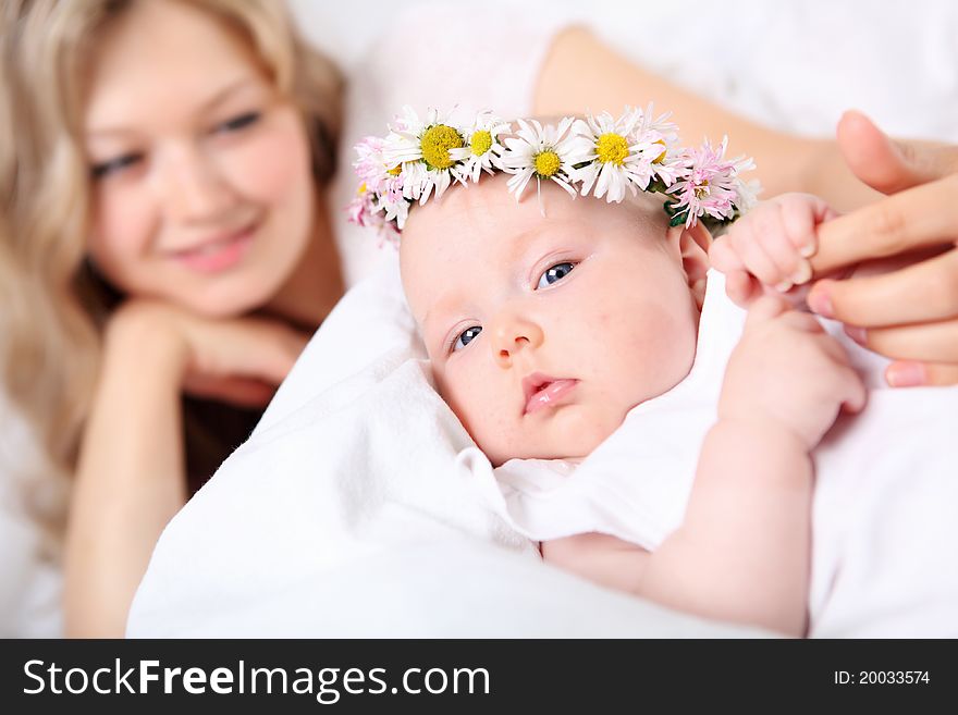 Portrait of a young mother and baby with a wreath of flowers on her head.