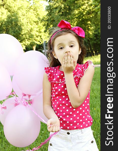 Close-up of a little girl standing in the park with pink balloons. Close-up of a little girl standing in the park with pink balloons