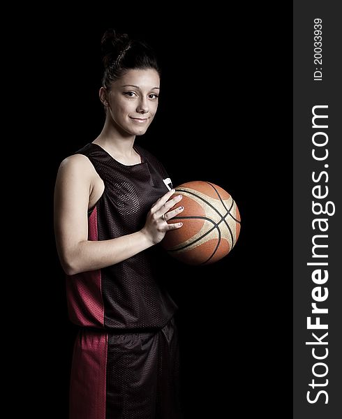 Smiling female basketball player, in black background