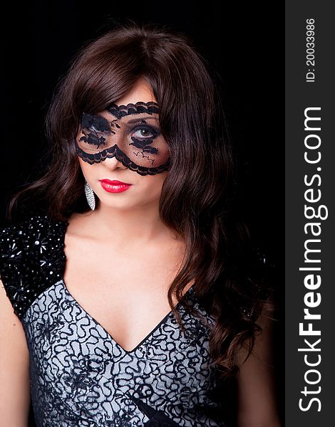 Portrait of attractive young brunette girl with long dark ringlets and lacy mask on her eyes on black background. Portrait of attractive young brunette girl with long dark ringlets and lacy mask on her eyes on black background