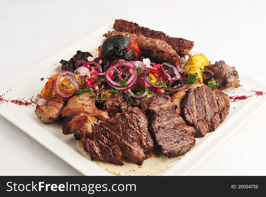 Meat allsorts with vegetables on a white plate