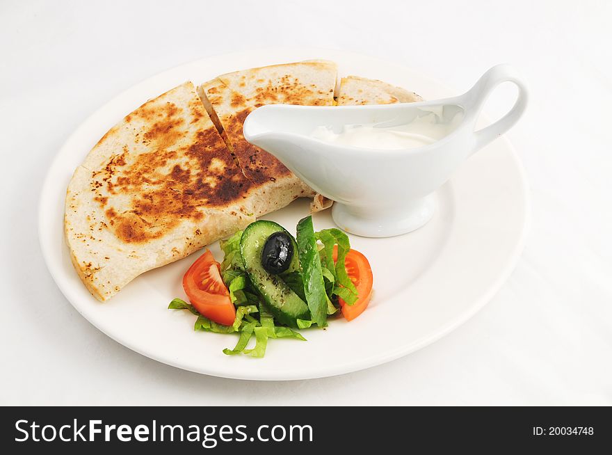 Baked flat cake with a garnish and sauce on a white plate