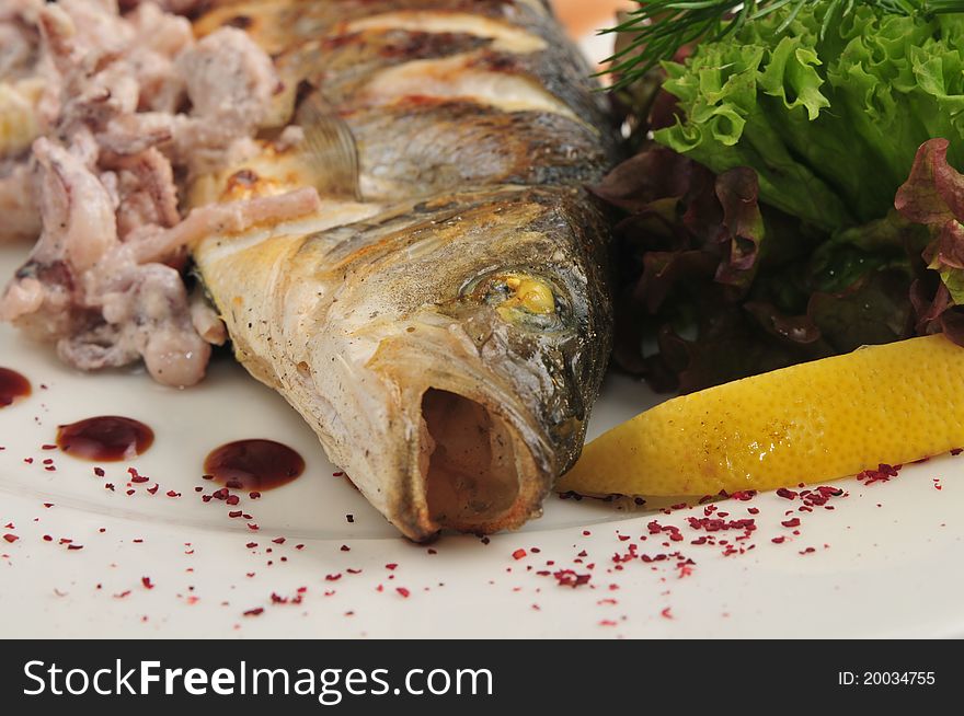 The fried fish with sauce and salad on a white plate