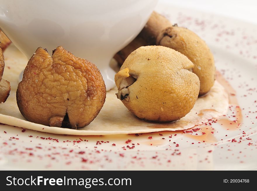 Mushrooms in hot fan with sauce on a white plate