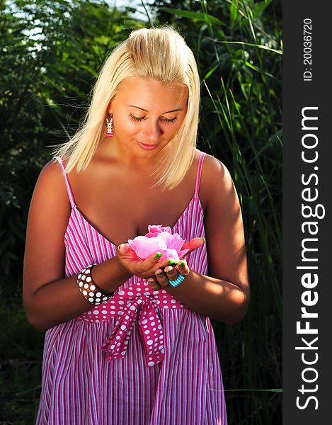 Young beautiful blonde girl with pink flower in hands. Young beautiful blonde girl with pink flower in hands