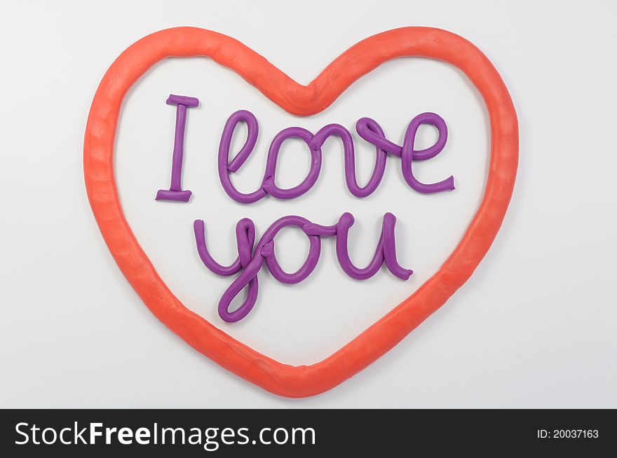 A plasticine lettering I love you inside a plasticine red heart.