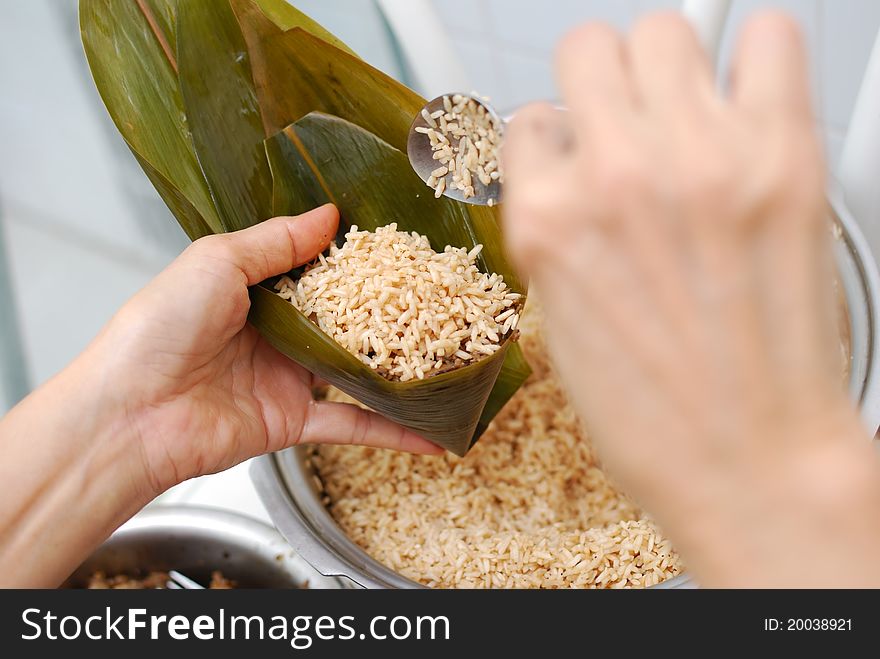 Filling rice into a triangular cone made from bamboo leaves. Asian style traditional cuisine. Filling rice into a triangular cone made from bamboo leaves. Asian style traditional cuisine.