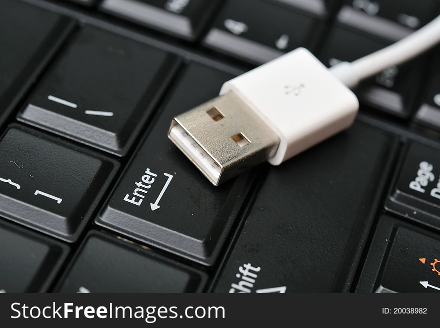 Macro of electronic data cable on black Enter key. Macro of electronic data cable on black Enter key.