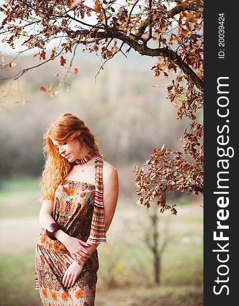 The red-haired girl in autumn leaves outdoor shot