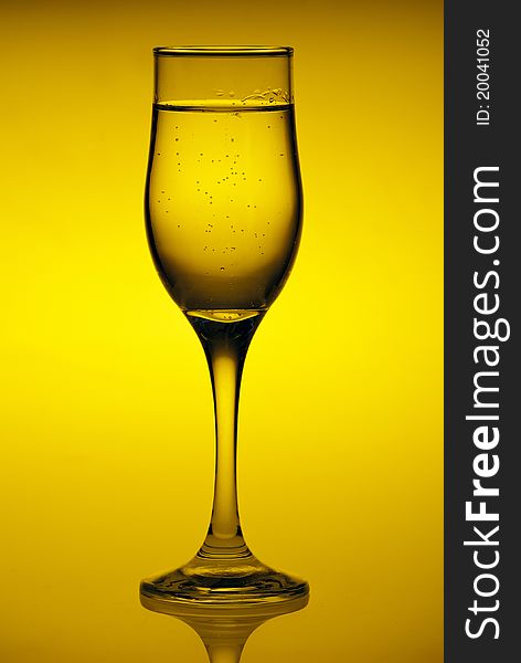 Glass with mineral water isolated on a yellow background
