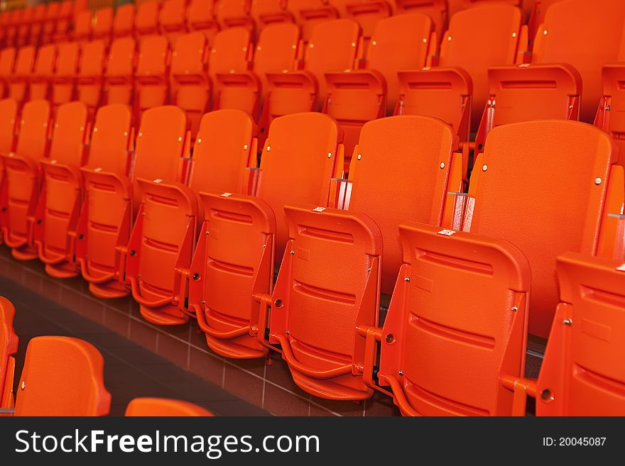 Orange, plastic seats in rows at sport indoor arena. Orange, plastic seats in rows at sport indoor arena.