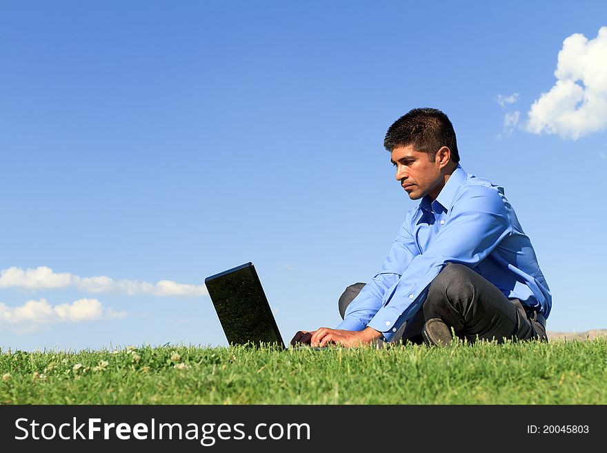 Young businessman working on his laptop at the park. Young businessman working on his laptop at the park