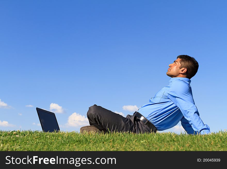 Young businessman with laptop relaxing on green grass. Young businessman with laptop relaxing on green grass