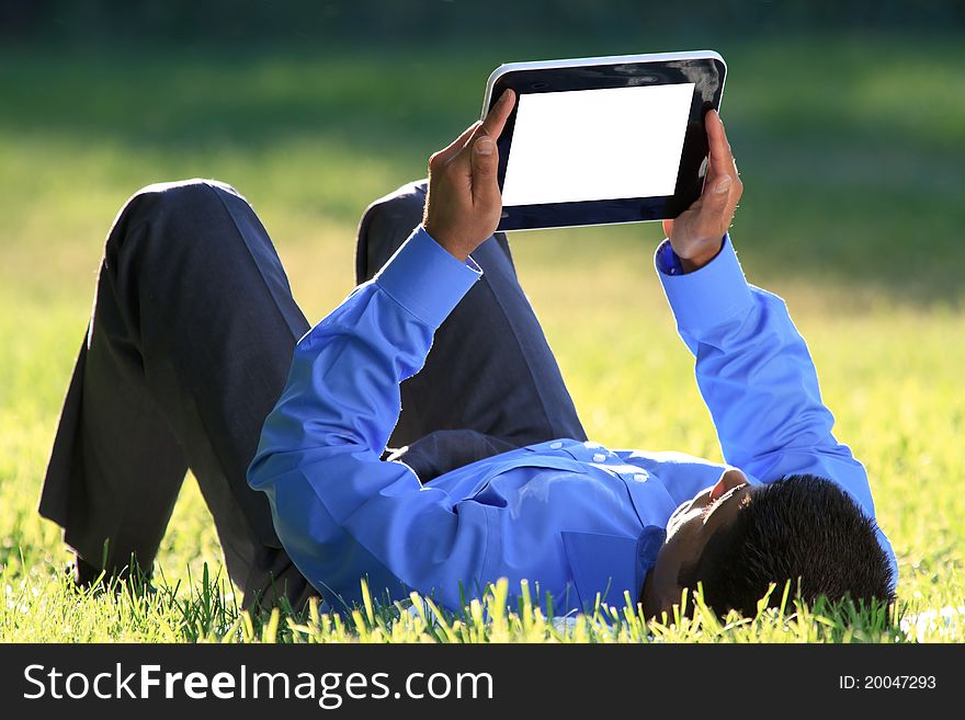 Young businessman relaxing on green grass with digital tablet in hands. Young businessman relaxing on green grass with digital tablet in hands