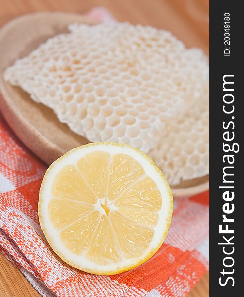 Honeycomb and half of lemon on orange tablecloth. Honeycomb and half of lemon on orange tablecloth