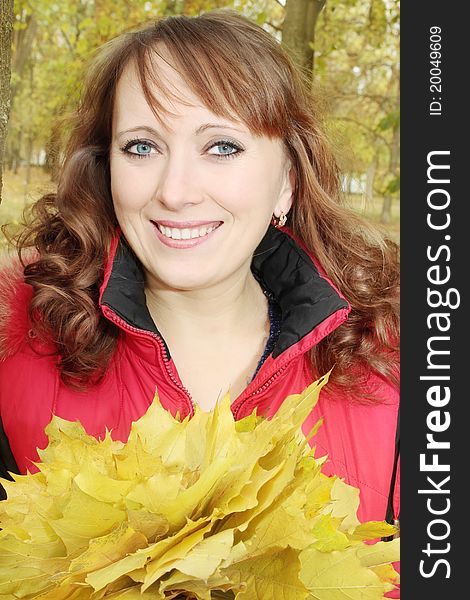 Happy woman in autumn holds the bouquet of leaves