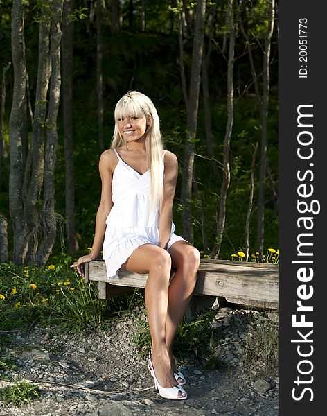 Girl in white dress sitting on a bench in the woods. Girl in white dress sitting on a bench in the woods