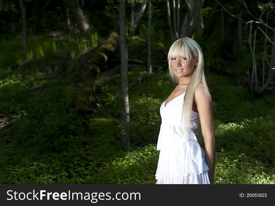 Girl in white dress standing in a dark forest. Girl in white dress standing in a dark forest